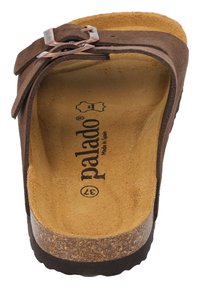 Sandalo scivoloso in suede marrone con soletta in sughero, cinturino in pelle regolabile e logo inciso. Suola piatta con un tacco leggermente rialzato.