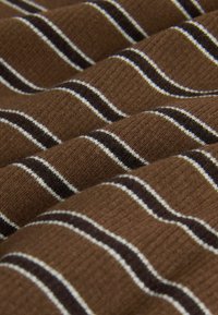 Tela marrón acanalada con rayas horizontales negras y blancas, doblada en suaves ondas.