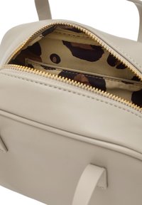 Jasno-beżowa skórzana torba z zamkiem błyskawicznym. Wnętrze charakteryzuje się podszewką w leoparda oraz kieszonką z zamkiem w złotym odcieniu.
