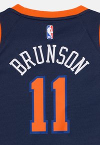 Mornarski košarkarski dres z oranžnimi akcenti. Vključuje "BRUNSON" v belem besedilu in številko "11" v oranžni barvi, obkroženi z modrim. Priložena oznaka NBA.