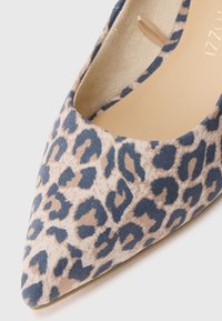 Προσαρμοσμένο παπούτσι σε λεοπάρ σχέδιο με μυτερή μύτη, που διαθέτει επάνω μέρος από μαλακό ύφασμα σε ουδέτερες αποχρώσεις τ ου μπεζ και του μπλε, με ομαλή υφή και ελάχιστες λεπτομέρειες.