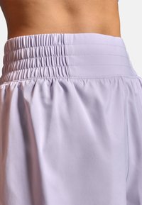 Lyse lavendelshorts med rynket taljebånd, glat tekstur og løs pasform. Har diskrete folder og ingen synlige metaldele.