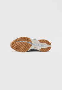 Semelle de chaussure Nike Zoom avec une surface en caoutchouc texturé, présentant un motif rainuré en marron et gris, et avec le logo "ZOOM" bien visible.