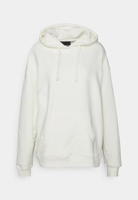 Sudadera con capucha color crema, con bolsillo tipo canguro, capucha con cordón ajustable y puños acanalados. Tejido suave con detalles mínimos de costura en la parte delantera.