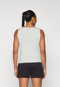 Top gri fără mâneci, realizat dintr-un material ribbed, cu decolteu rotund și o croială strânsă, completat cu pantaloni scurți negri. Design curat și simplu.