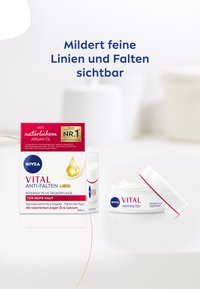 NIVEA VITAL Anti-Falten cream in a white jar with a red accent, labeled for mature skin, alongside a product box featuring a golden droplet.