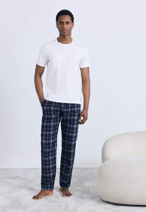 Vit t-shirt med korta ärmar kombinerad med marinblå och rutig byxa. Outfiten har en avslappnad passform och minimalistiska designdetaljer.