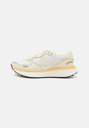 Weiße und beige Sneakers mit einer glatten Lederaußenfläche, strukturierten Akzenten, einer gepolsterten Sohle und einer schwarzen Gummisohle.