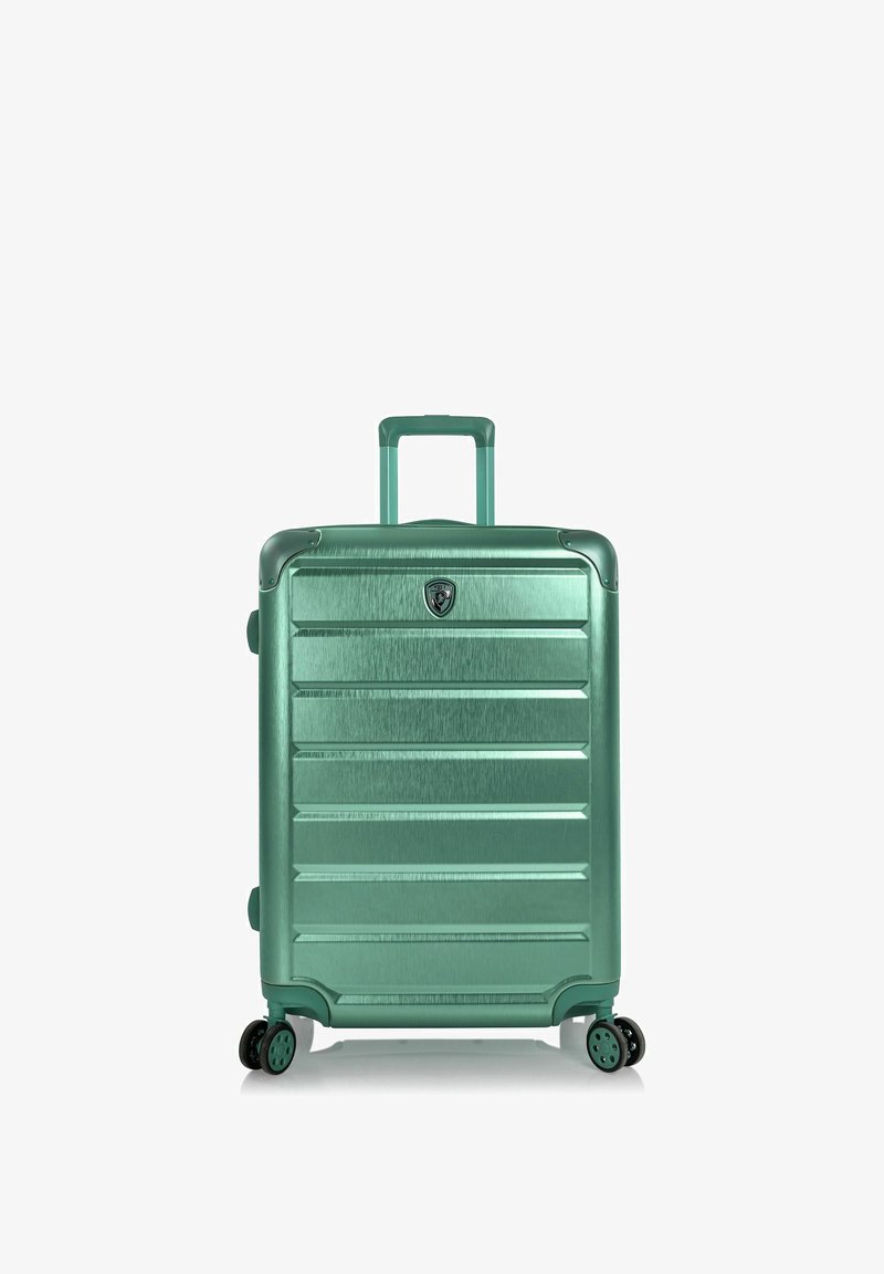 Valise rigide verte avec poignée télescopique et quatre roues multidirectionnelles vue de face sur fond blanc.