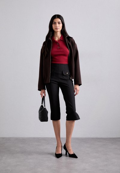 Brun zip-up jacka, ribbad röd polo skjorta, svarta cropped byxor med utsvängd fåll, svarta klackar och en liten svart väska. Släta, åtsittande texturer.