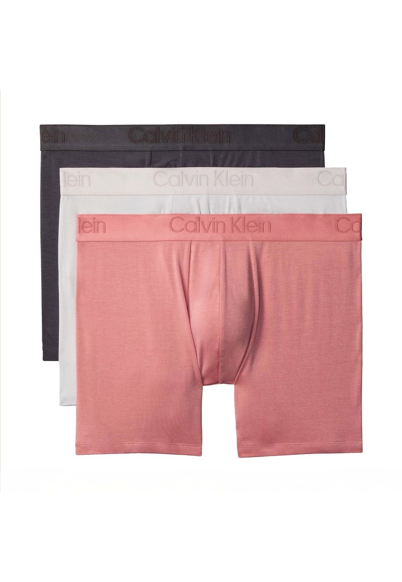 Drie herenboxershortjes gestapeld, kleuren roze, wit en donkergrijs, elk met het Calvin Klein-logo op de tailleband.