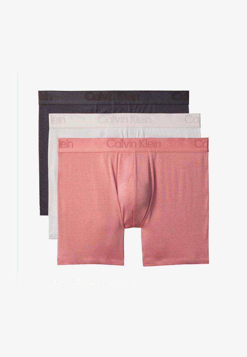 Drie herenboxershortjes gestapeld, kleuren roze, wit en donkergrijs, elk met het Calvin Klein-logo op de tailleband.