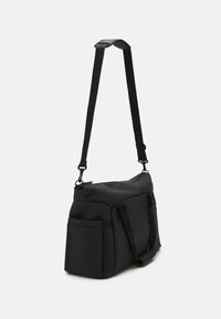 Sac à bandoulière noir en matériau lisse, doté de bretelles réglables, d'un compartiment principal et de poches latérales. Design minimaliste sans embellissements.