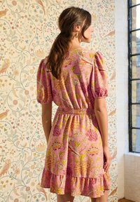 Rochie din material floral roz cu manșoane bufante, talie elastică și tiv cu volane în trepte. Prezintă flori multicolore pe un fundal texturat.