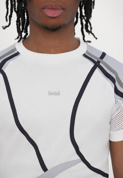 Weißes T-Shirt mit kurzen Ärmeln, das dunkelblaue und graue Designlinien aufweist, strukturierte Mesh-Akzente an den Ärmeln und ein dezentes "GmbH"-Logo.