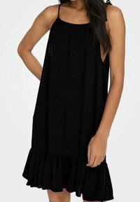 Vestido negro sin mangas con un corte holgado, escote fruncido y dobladillo con volantes. Fabricado en una tela ligera, cae suavemente.
