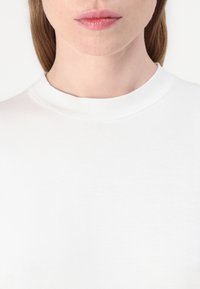 Witte crew neck t-shirt met een gladde textuur, met een minimalistisch ontwerp en zonder zichtbare patronen of versieringen.