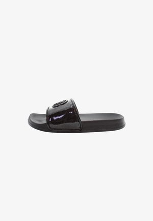 Black slide sandal with a glossy finish, featuring a wide strap and textured sole. The strap includes a round emblem as a notable detail.