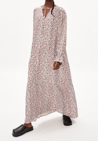 Robe maxi fleurie en tissu léger et aérien, dotée d'une coupe ample, de manches longues et d'un décolleté en forme de goutte. Le motif comprend de petites fleurs rouges et bleues.