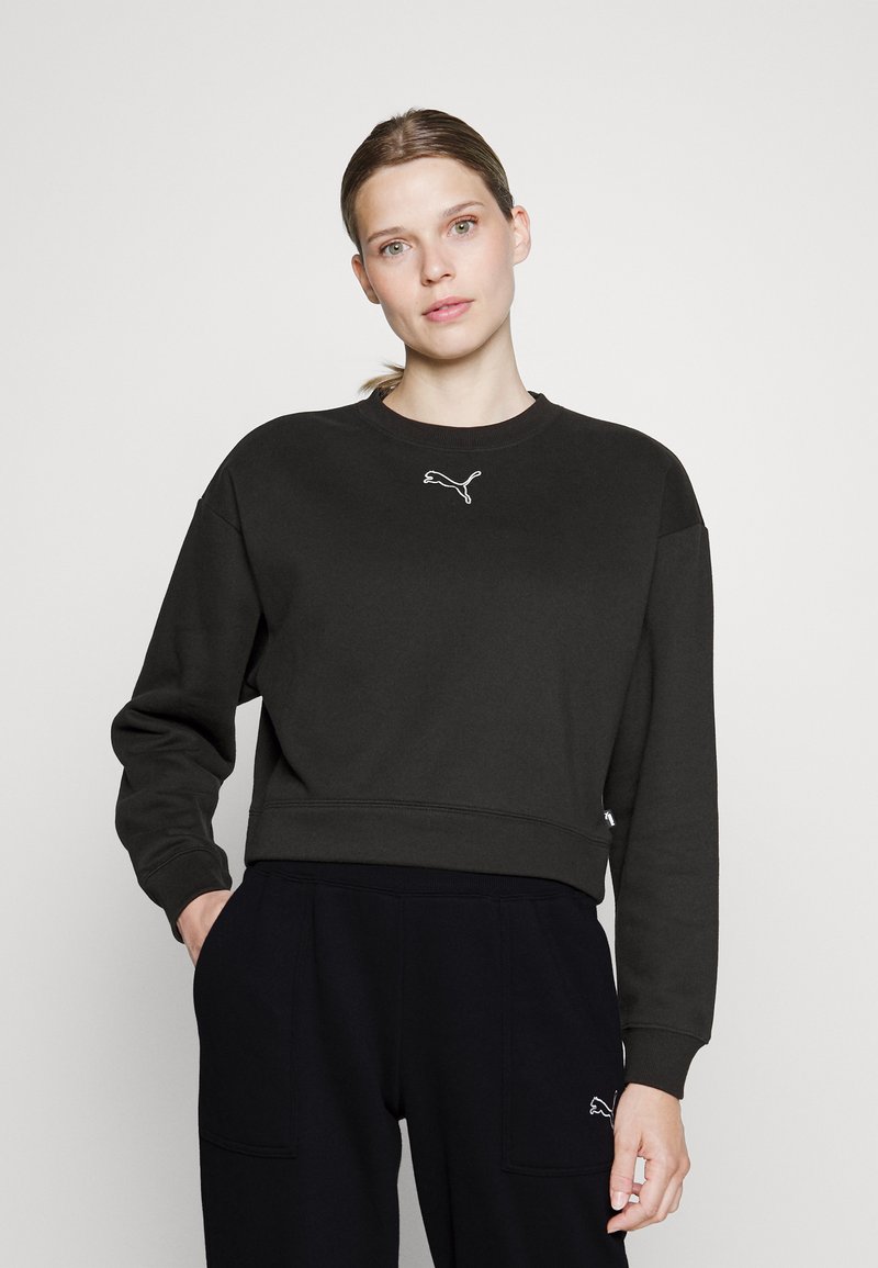 Felpa nera corta con collo rotondo e maniche lunghe, caratterizzata da un logo Puma bianco sul petto. Il tessuto sembra morbido e texturizzato.