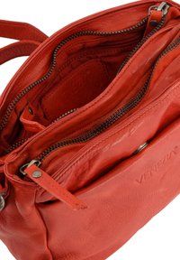 Rode leren tas met meerdere ritscompartimenten, textuur materiaal en een reliëflogo. De binnenkant heeft een zachte voering.