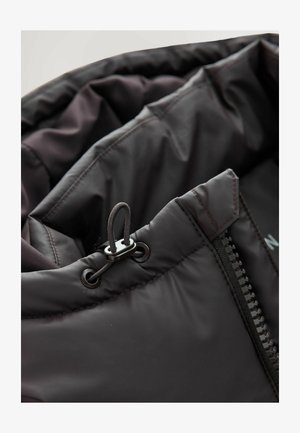 Schwarze Pufferjacke mit glattem, glänzendem Innenfutter. Verfügt über einen Reißverschluss und eine verstellbare Kordel mit einem Kunststoffstopper.