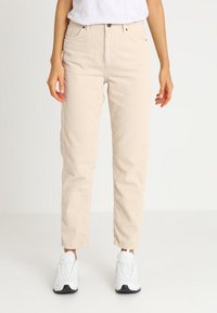 Beige corduroy pants with a straight-leg design, featuring front pockets, a high waist, and paired with white sneakers.