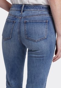 Hoge taille blauwe denim jeans met een licht vervaagde textuur, met twee achterzakken, contrasterende stiksels en een ritsluiting.