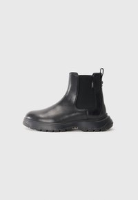 Bottines Chelsea en cuir noir avec panneaux latéraux �élastiques, bout rond, semelle en caoutchouc texturé et une languette à l'arrière pour un enfilage facile.