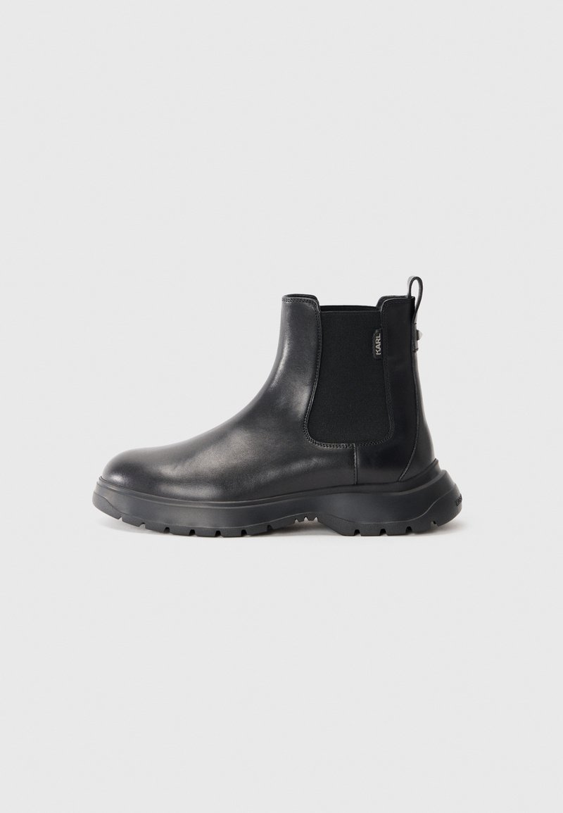 Bottines Chelsea en cuir noir avec panneaux latéraux élastiques, bout rond, semelle en caoutchouc texturé et une languette à l'arrière pour un enfilage facile.
