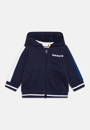 Marineblå hættetrøje til småbørn med hvide og blå striber på ærmerne, forlommer, fuld lynlås og Timberland-logo på brystet.