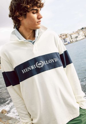 Polo shirt blanc à manches longues avec une bande horizontale marine arborant le logo "HENRI LLOYD". Matière en coton doux, design avec col, coupe décontractée.