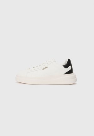Hvite sneakers med en teksturert stoffoverdel, svart hælakkent, flate snøring og tykk hvit såle. Har et metallisk logo på siden.
