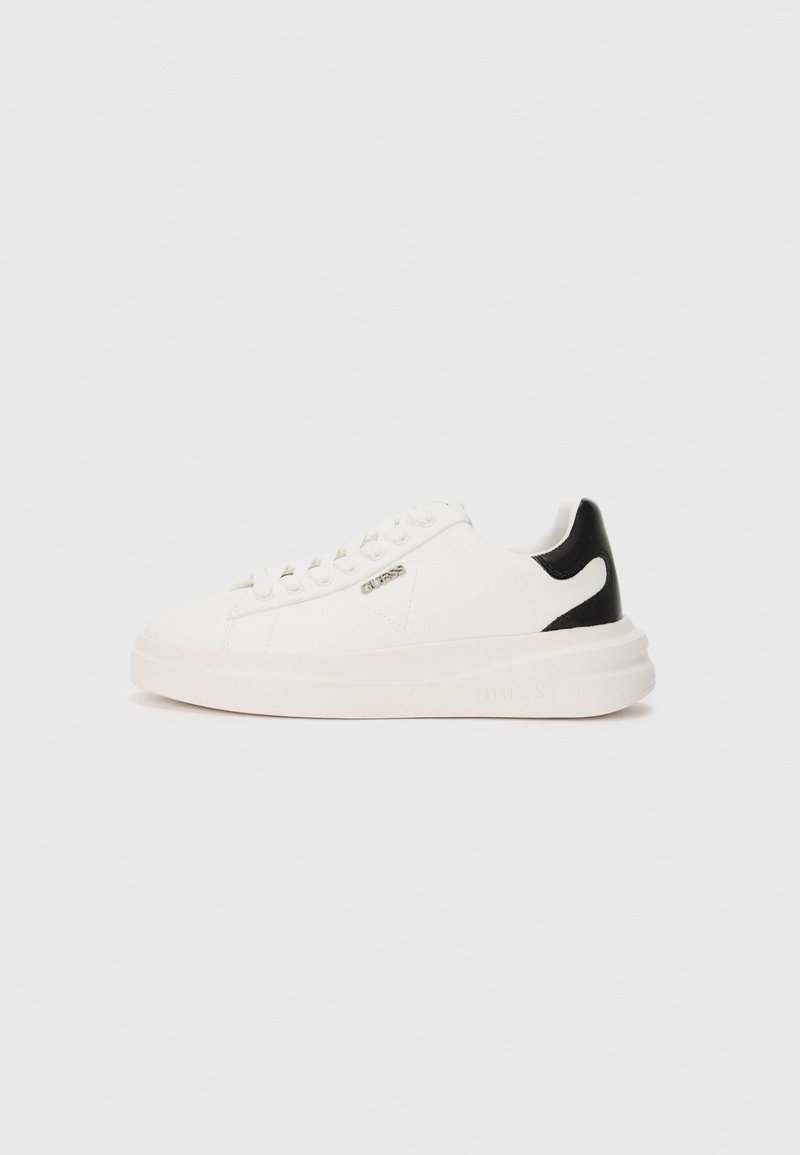 Hvite sneakers med en teksturert stoffoverdel, svart hælakkent, flate snøring og tykk hvit såle. Har et metallisk logo på siden.