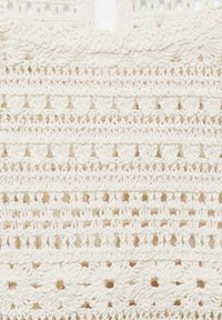 Szydełkowana tkanina w kolorze kremowym, złożona z misternych wzorów z powtarzającymi się motywami florystycznymi i geometrycznymi, wykonana z teksturowanej włóczki.