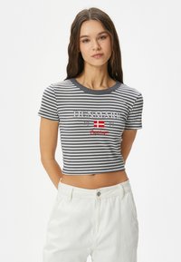 Randig grå och vit croppad topp med korta ärmar, med texten "DANMARK" och en dansk flagga i grafik. Ribbad struktur och rund halsringning.