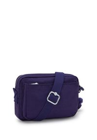 Kompaktowa torebka crossbody w głębokim fioletowym kolorze z regulowanym paskiem, przednią kieszenią na zamek i miękką teksturą materiału na białym tle.