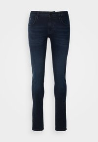 Jean skinny bleu foncé avec poches avant, passants de ceinture et fermeture par bouton, présenté sur un fond uni clair.