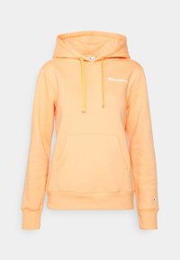 Oranssi huppari, jossa on kengurutasku, kiristysnyöri ja kirjailtu logo rintakehässä. Pehmeä kangas ja resorit hihansuissa.