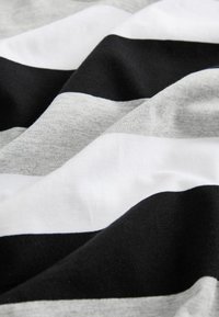 Tissu rayé noir, blanc et gris avec une texture douce, présentant des lignes horizontales épaisses et fines alternées dans un agencement ondulé.