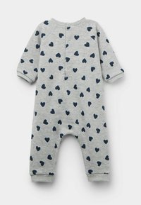 Une combinaison en coton gris avec des motifs de cœurs navy, des manches longues, des poignets côtelés et une fermeture à pression à l'arrière. Texture douce partout.