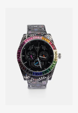 Reloj negro con correa de patrón floral, esfera con diseño de calavera, tres subdiales y un bisel multicolor con piedras rectangulares.
