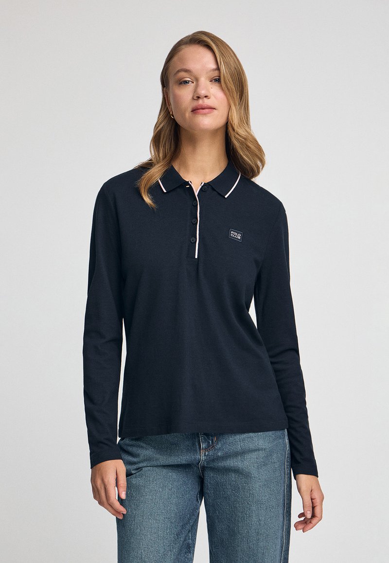 Granatowa koszulka polo z długim rękawem, z kołnierzykiem zapinanym na guziki, różowym wykończeniem i logo na piersiach. Miękka bawełniana tkanina, luźny krój.