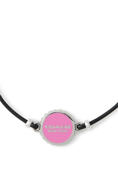 Bracelet en cuir noir avec un pendentif circulaire en argent au centre rose, gravé "COACH NEW YORK", accompagné de petits anneaux en argent.