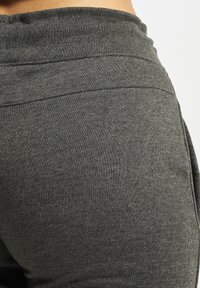 Pantalons joggers en mélange de coton gris avec une taille ajustée, surface texturée et design fuselé. Aucuns motifs ou éléments matériels visibles.