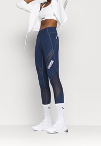 Marina leggings med nätinsatser, med en figursydd design, kontrasterande paneler och en vit logotyp. I kombination med vita sneakers och strumpor.