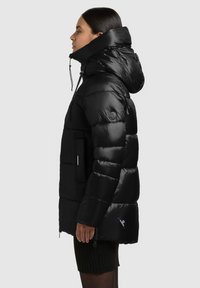 Czarna kurtka puchowa z wysokim kołnierzem, dużym kapturem i pikowanym wzorem. Posiada boczne kieszenie oraz naszywkę z logo na rękawie.