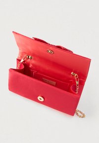 Crvena satenska torbica s magnetnim zlatnim zatvaračem, lancem i unutarnjim pretincem, fotografirana otvorena na bijeloj pozadini.