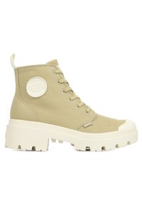Stivaletti alla caviglia in tela beige con punta rotonda, suola in gomma bianca spessa, lacci frontali e una toppa con logo circolare sul lato.