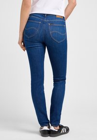 Blå denim skinny jeans med hög midja, väldefinierade sömmar och två bakfickor. Tyget har en slät yta och minimal blekning.
